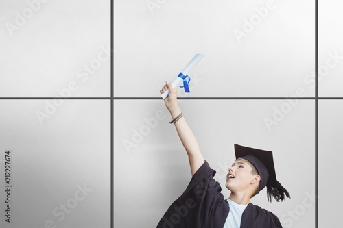 Composite image of student in mortarboard holding degree