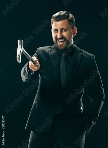 The barded man in a suit holding cane.