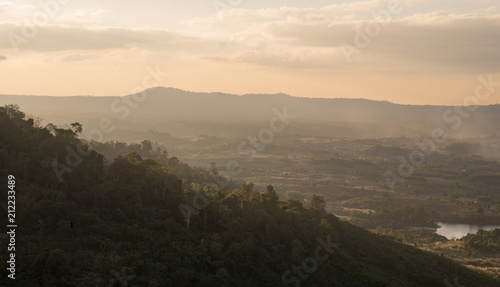 a landscape view of village in the middle of green mountains during sunset time.