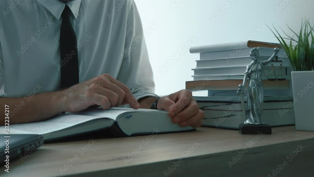 Lawyer reading law book in the office. Footage contains generic figurine of Lady Justice, a personification of moral force and it's origin is Justitia, goddess of Justice in Roman mythology