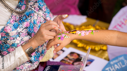 A Beautiful Thai woman in Thai transnational dress was painting kid's hand with paintbrush in Thailand Grand Festival in Sydney, 24-25/03/18. Australia