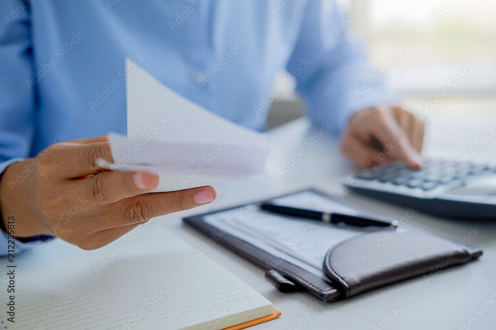 Woman with bills and calculator. Woman using calculator to calculate bills at the table in office. Calculation of costs. Woman with bills and calculator. Woman using calculator to calculate bills at the table in office. Calculation of costs.