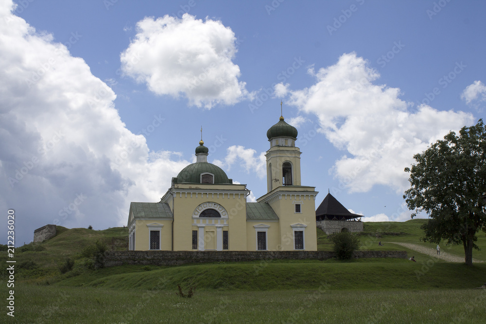 Photo of ancient Khotyn church near the castle in Ukraine at the day time in summer under extremely fluffy clouds Photo of ancient Khotyn church near the castle in Ukraine at the day time in summer under extremely fluffy clouds