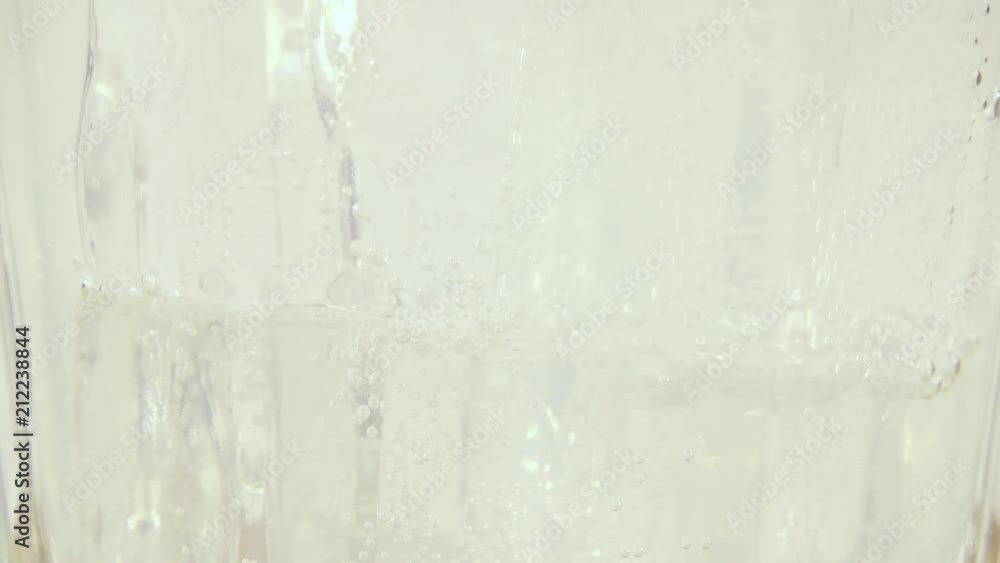 Pour a fizzy muddy white drink into a glass of ice close-up Pour a fizzy muddy white drink into a glass of ice close-up