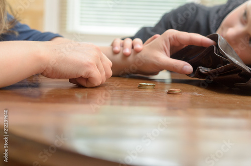 A sad woman at the table thinks the last coins. Empty wallet - boy son calms mother.