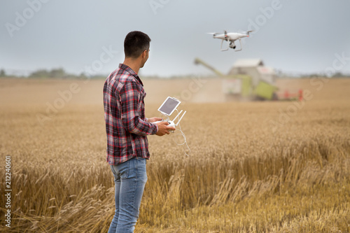 Farmer driving drone above wheat field during harvest