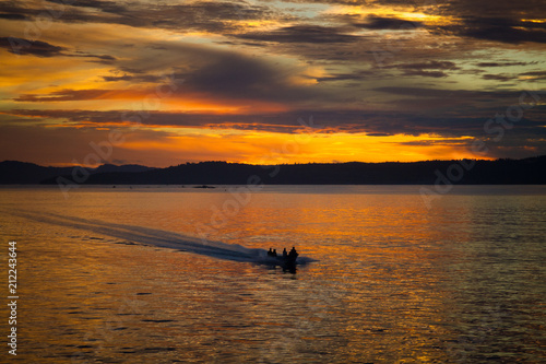 The fisherman are cruising to the ocean for fishing on beautiful golden sunrise