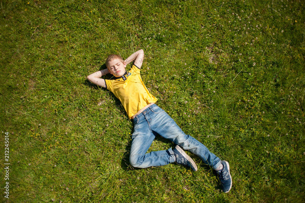 The boy is lying on the grass.