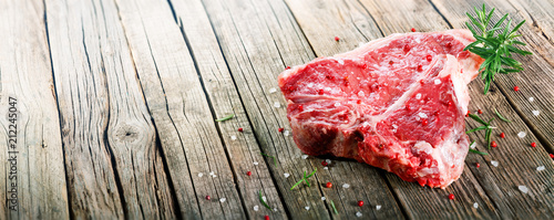 Raw T-Bone Steak  On Wooden  With Rosemary And Pink Pepper
