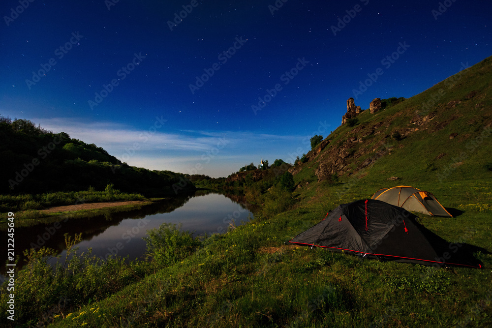 tourist tents at riverbank at summer night