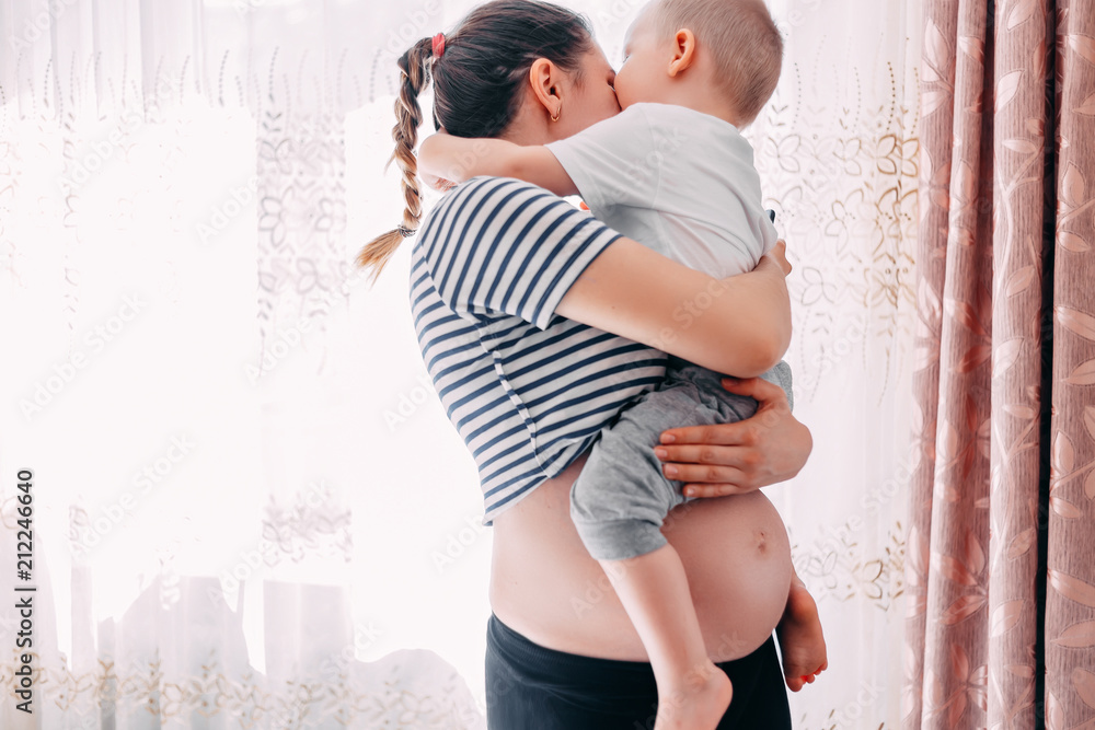Pregnant women holds her first child. Eldest kid in arms. Elder brother Pregnant women holds her first child. Eldest kid in arms. Elder brother