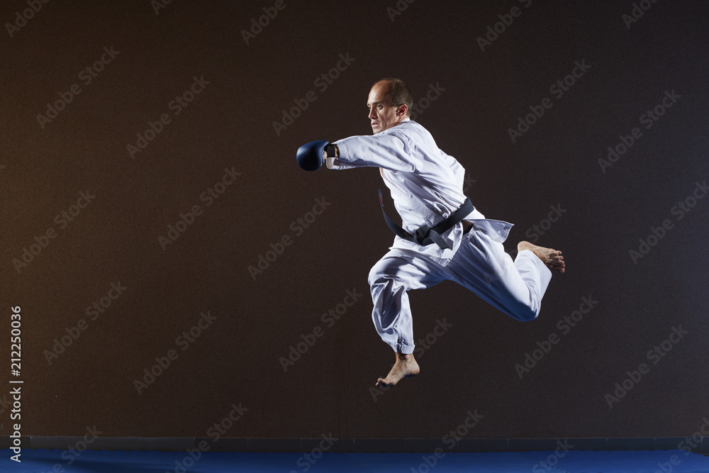A man with blue overlays on his hands strikes with a hand in a jump