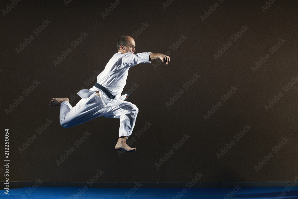 A sportsman in karategi trains punch hand in jump