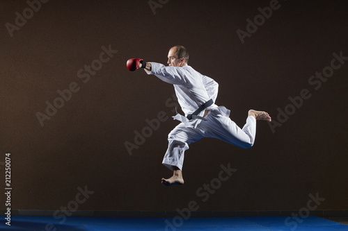 Adult athlete in karategi beats with a hand in a jump