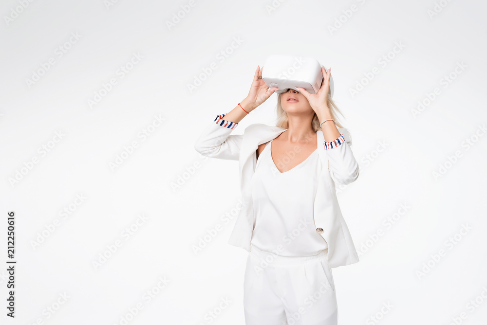Blond woman in white suite with virtual reality goggles. Studio shot on white background Blond woman in white suite with virtual reality goggles. Studio shot on white background