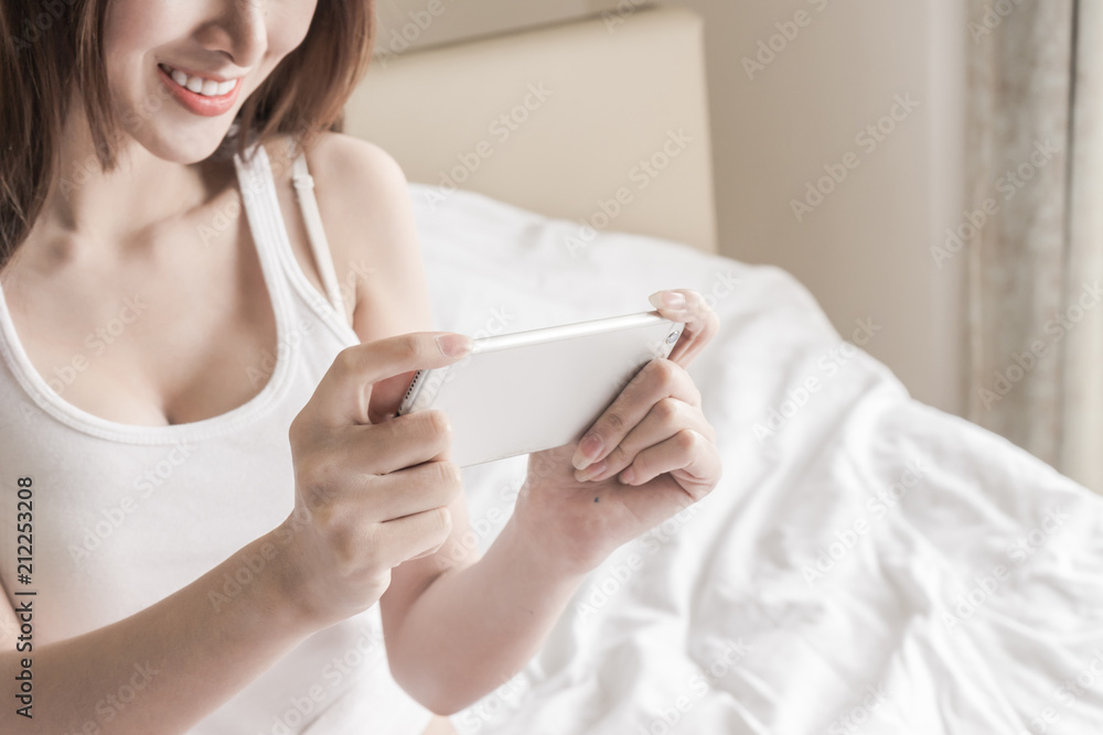 Happy Asian woman hold smartphone and smile in bedroom Happy Asian woman hold smartphone and smile in bedroom