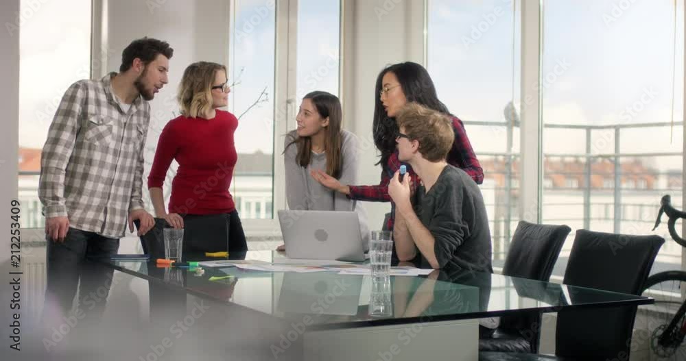 Group of students with positive mindset preparing presentation on a modern conference table with laptop and sheets