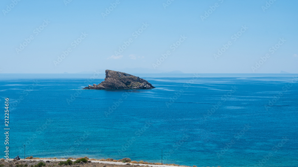 A shark fin shaped rock across komito beach at Syros greek island, Cyclades, Greece