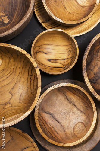 Wooden utensils for the kitchen, bowls, plates on a black background. The concept of natural dishes, a healthy lifestyle. Texture of wood. Wooden eco-ware
