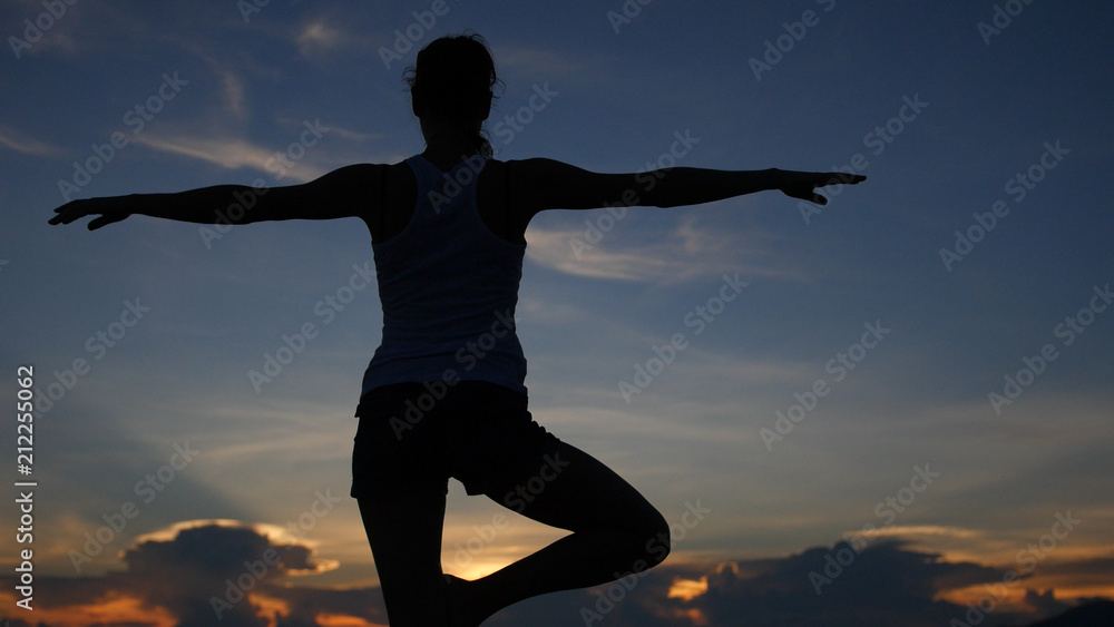A slender girl does a stance in yoga with a beautiful view of the sea and the sunset. HD