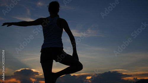 A yogi girl stands in the asana on the seashore and sunset with the movement of the camera. HD