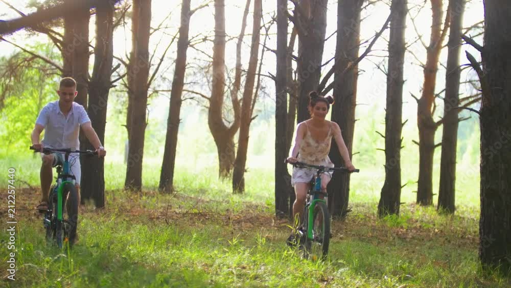 Happy couple cycling on the path in the pine forest Happy couple cycling on the path in the pine forest