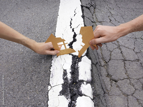 Divorce fighting couple hands pull apart house on white line on asphalt road arguments shrink concept photo