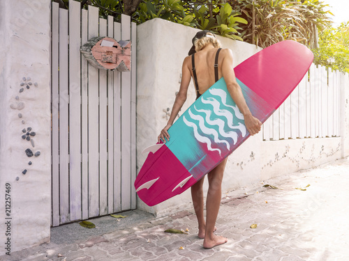 Woman with pink surf board standing on a beach surf house space