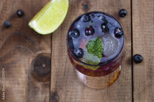 a small glass of a cocktail cool blueberry drink with berries on top