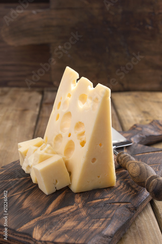 Traditional Dutch cheese with holes, on a vintage wooden board, wooden background. Dairy. Copy space.