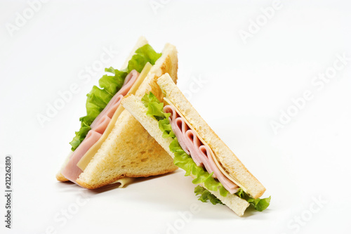 Two triangular sandwiches with cheese and ham. The sandwich is made from slices of fried white bread. Close-up. White background.