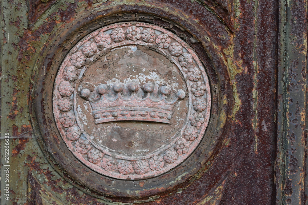 Part view of an old, rusty door of a crypt in Berlin-Germany. A weathered crown