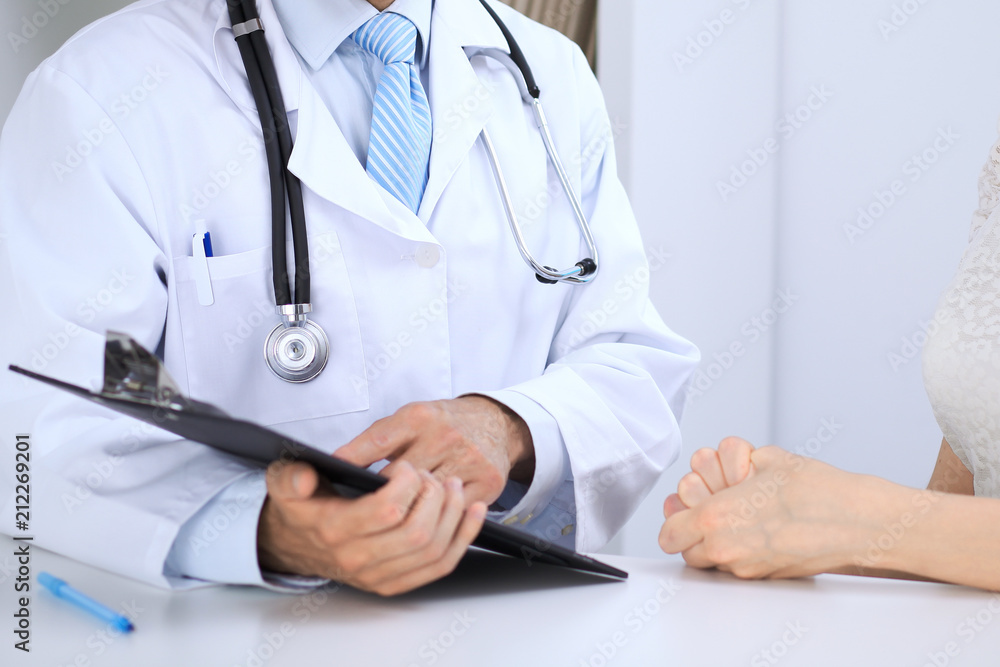 Doctor and patient talking while sitting at the table . Concept of support and trust in medicine Doctor and patient talking while sitting at the table . Concept of support and trust in medicine