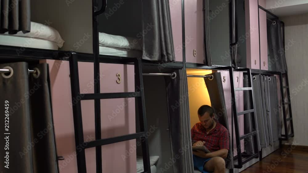 A man is sitting with aipad. A woman descends the stairs from the capsule in the hotel A man is sitting with aipad. A woman descends the stairs from the capsule in the hotel