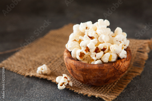 Popcorn in a olive wooden bowl on a dark background