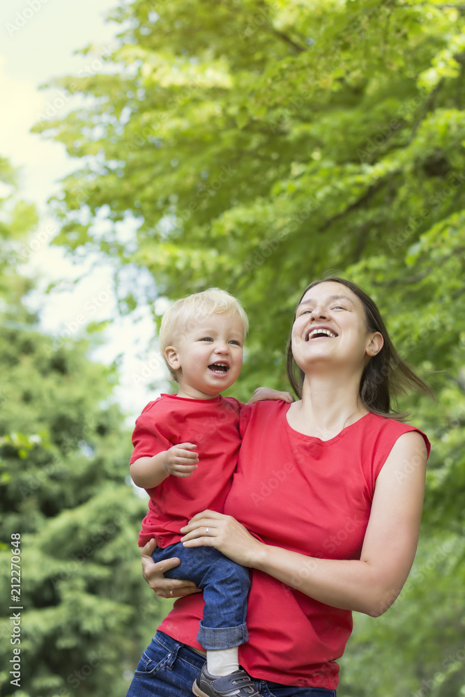 Mother and her cute toddler son playing outdoor. Family look clothing. Copy space Mother and her cute toddler son playing outdoor. Family look clothing. Copy space