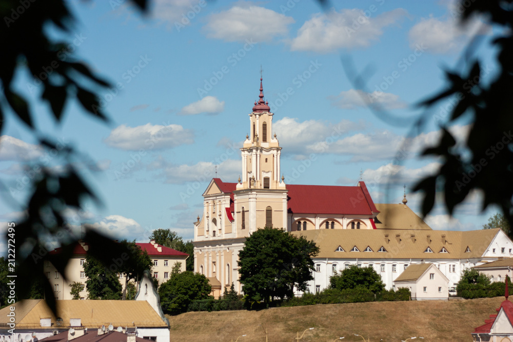 Sights and views of Grodno. Belarus. Bernardine church and monastery in the frame of branches, from the side of the river Neman.