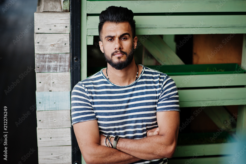 Handsome tall arabian beard man model at stripped shirt posed outdoor. Fashionable arab guy. Handsome tall arabian beard man model at stripped shirt posed outdoor. Fashionable arab guy.