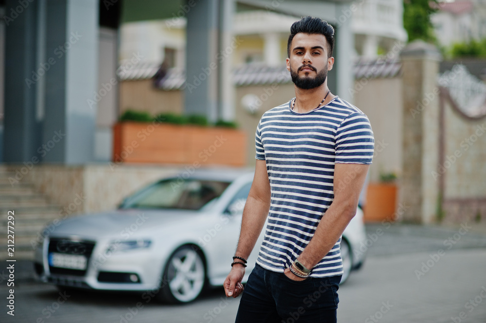 Handsome tall arabian beard man model at stripped shirt posed outdoor against car. Fashionable arab guy. Muslim businessman.
