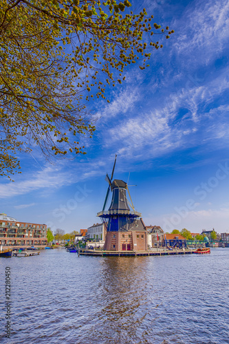 Travel Destinations Concepts. Picturesque View of Harlem Cityscape With De Adriaan Windmill on Spaarne River At Background During Daytime.