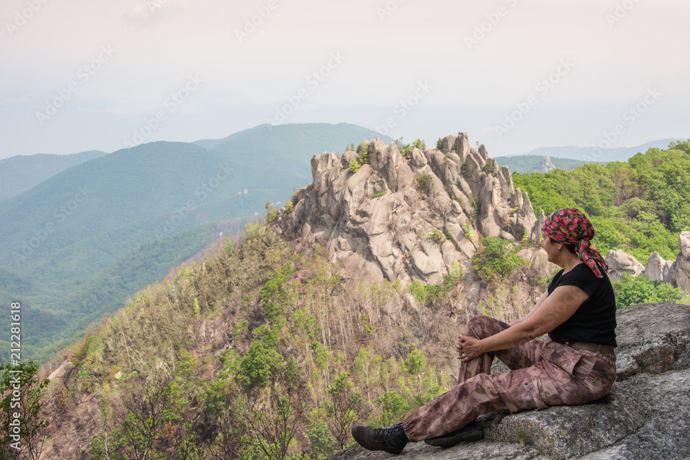 The climber rests on a cliff on the edge of the abyss against the background of picturesque rocks