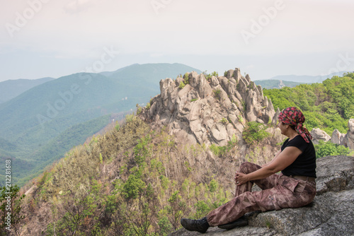 The climber rests on a cliff on the edge of the abyss against the background of picturesque rocks