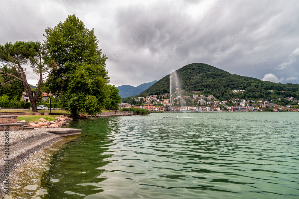 Landscape of Lake Ceresio with fountain in Lavena Ponte Tresa, province of Varese, Italy