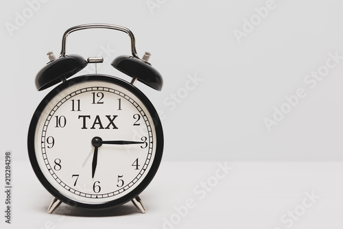 A black clock on light color background. Tax time alert.