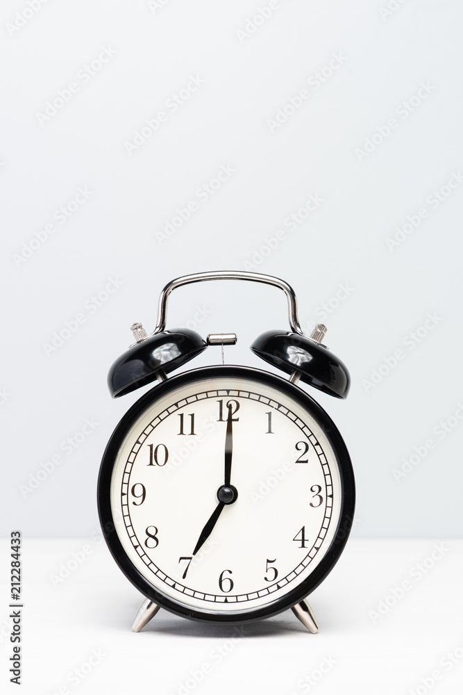 A black clock isolated on light color background. A black clock isolated on light color background.