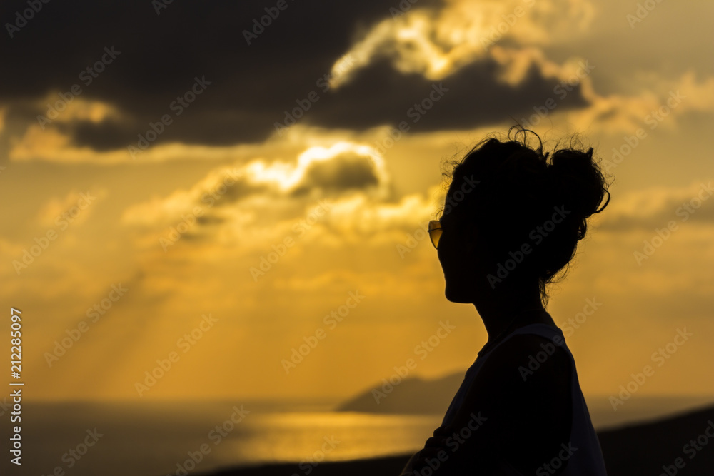 Woman silhouette over an horizon dominated by the sunset over the Greek Islands at Crete