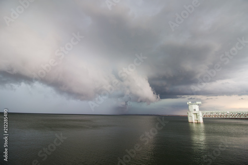A supercell thunderstorm and shelf cloud loom over a lake. All boats haves evacuated for this tornado-warned storm.	