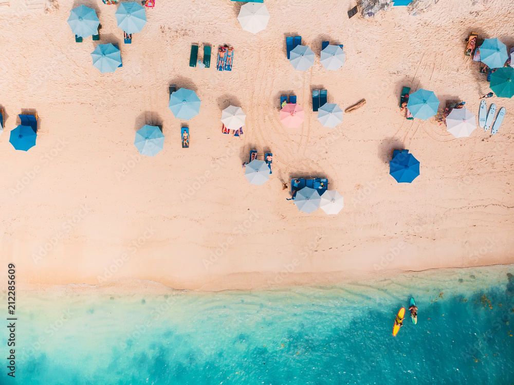 Top view of sandy beach with turquoise sea water and colorful blue umbrellas, aerial drone shot - obrazy, fototapety, plakaty 