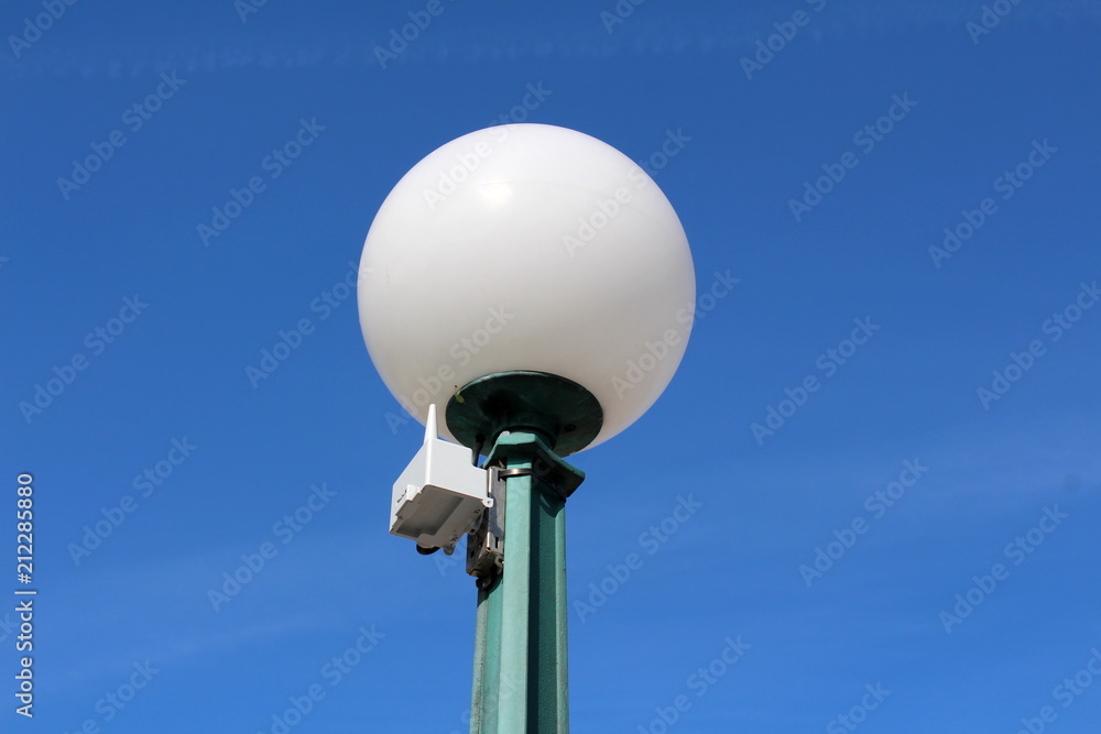 Street lamp post with small wireless antenna on clear blue sky background Street lamp post with small wireless antenna on clear blue sky background