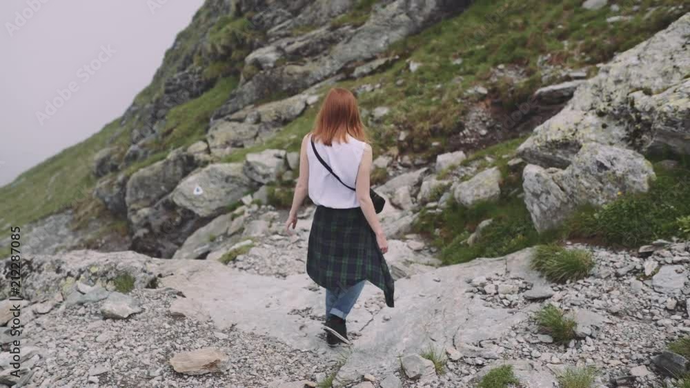 A young woman hiker climbs mountains with photo camera. Transfagarasan, Carpathian mountains in Romania A young woman hiker climbs mountains with photo camera. Transfagarasan, Carpathian mountains in Romania